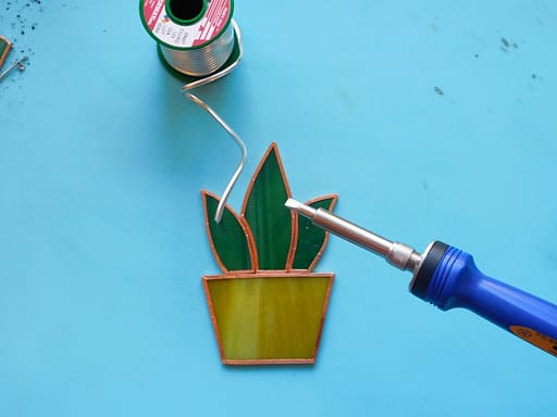 Soldering iron and lead free solder working on stained glass aloe plant Mountain Woman Products