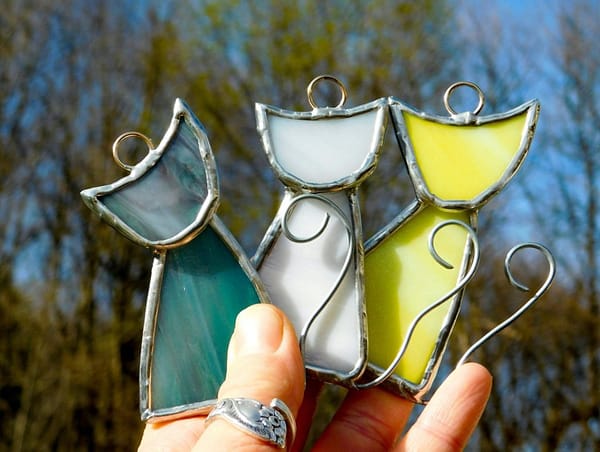 Photo of stained glass cat suncatchers in blue, white and yellow