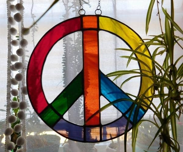 rainbow stained glass peace sign lead free hanging in window with plants Mountain Woman Products